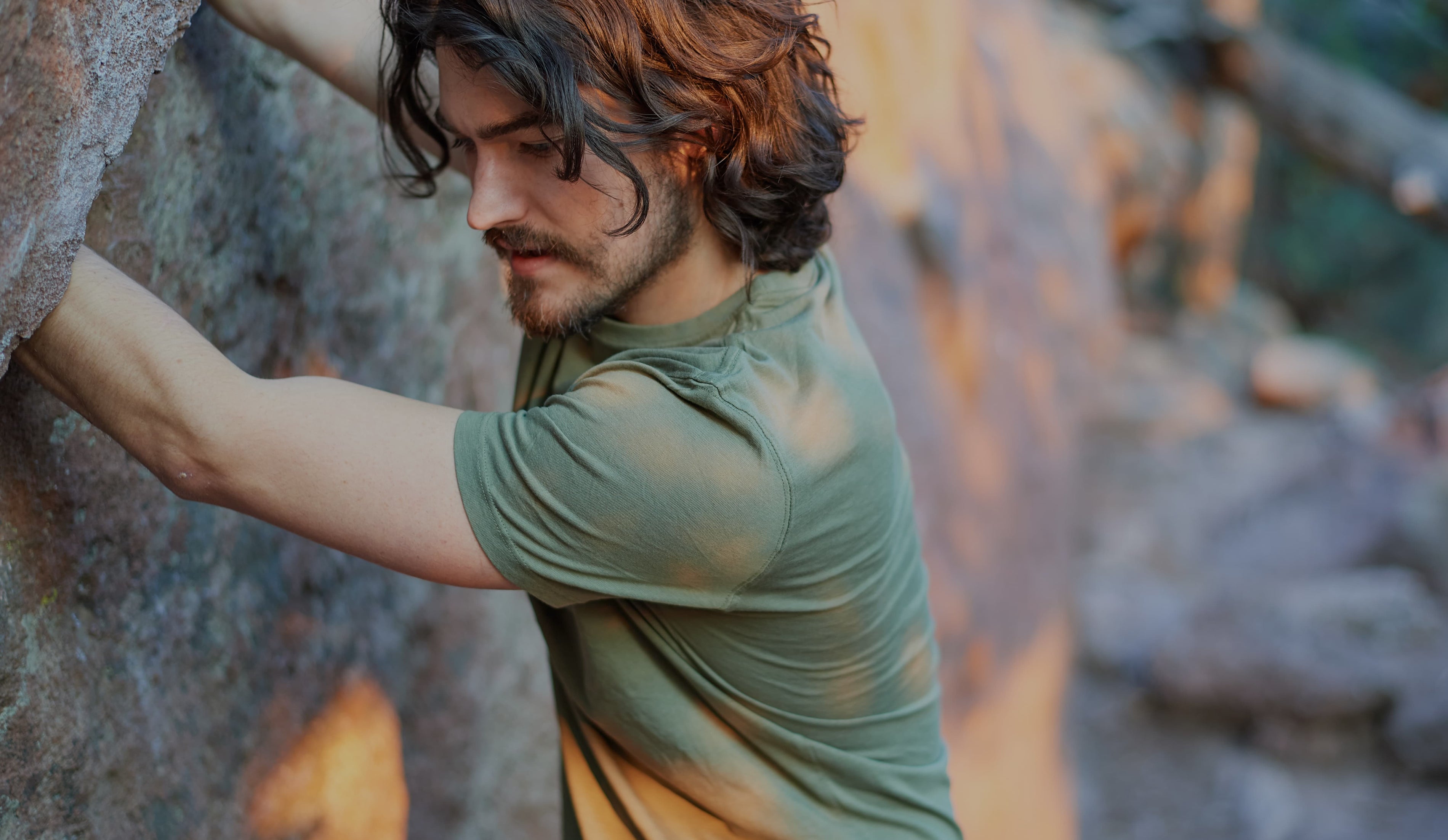 Man wearing a green ONNO organic cotton t-shirt while rock climbing
